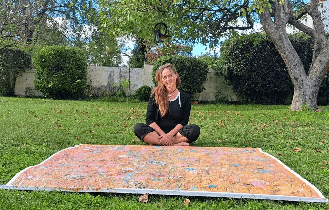 Artémis assise près d’une grande toile posée dans l’herbe